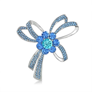Macro shot of bow brooch with blue crystals and floral center on a silver metal base