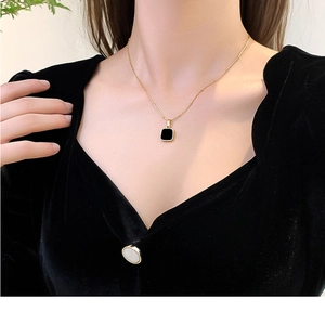 Detail of a minimalist black square pendant on a 18k gold plated stainless steel necklace