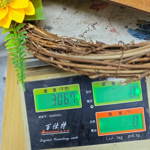 Détail de la couronne de tournesols montrant un poids de 306,7g sur une balance