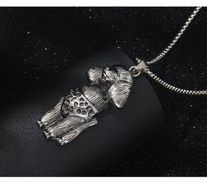 Detail of silver poodle puppy pendant on a sleek snake chain over a dark background