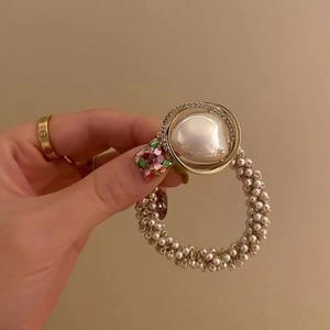 Detailed view of elegant pearl hair tie with large central pearl and rhinestone halo