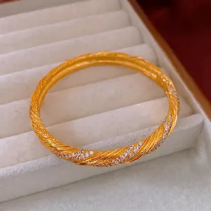 Vintage gold plated twisted bangle with zircon stones displayed in a white jewelry gift box