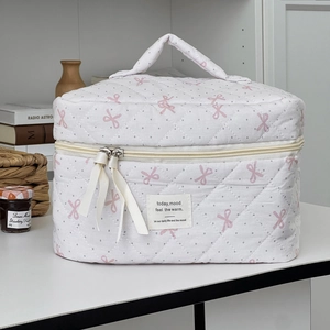 Pink polka dot bow makeup bag with quilted texture and top handle for travel storage