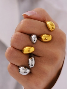 Macro shot of minimalist gold and silver teardrop rings with smooth mirror finish metal