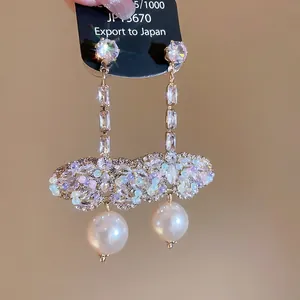 Elegant gold drop earrings featuring butterfly rhinestones and round white pearls
