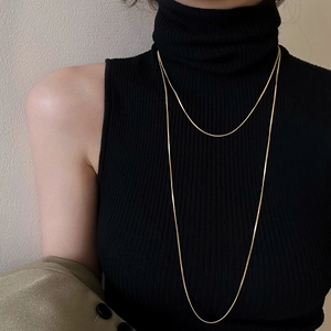 Elegant gold double-layer snake chain necklace worn over a black sweater top
