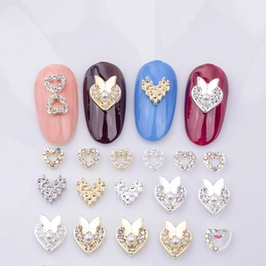 Detailed close-up of heart and butterfly alloy nail art charms with pearls and rhinestones