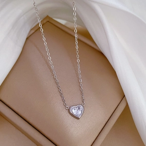 Macro detail of a heart-shaped zircon pendant on a silver titanium steel chain