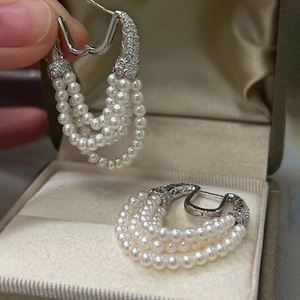 Detailed view of silver horseshoe earrings with white pearls and zircon tassels