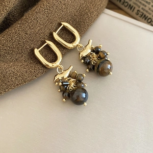 Detail view of bird design gold tassel earrings with polished tiger eye stone beads