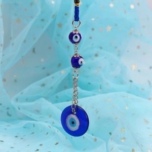Macro detail of blue glass Evil Eye charms with silver chain and decorative fringe
