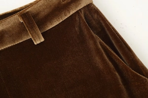 Detailed close-up of brown velvet trousers featuring refined stitching and pocket design