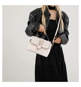 Close-up of elegant pink leather handbag with gold buckle styled with black jacket