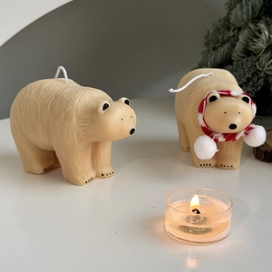 Polar bear candles with striped scarf and lit scented jar in warm home setting