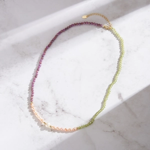 Macro shot of S925 silver beaded necklace with purple, green beads and pearls on marble
