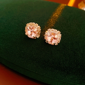 Macro shot of pink round halo stud earrings with crystals on green velvet padding