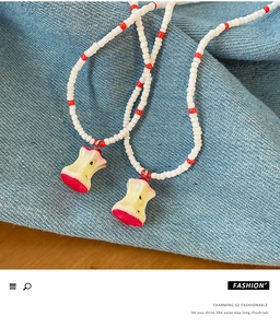 Detail of beaded summer necklace with unique apple core resin pendant on denim background