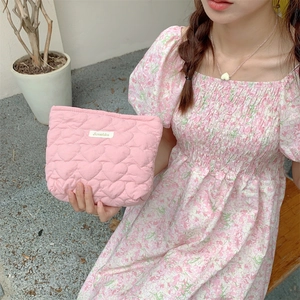 Detailed view of pink quilted heart texture and fabric label on a large makeup pouch