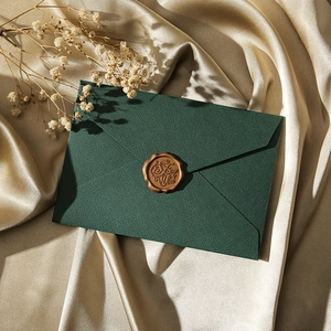 Detail of dark green envelope with brown wax seal on champagne silk fabric background