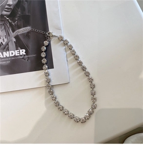 Close-up of a silver-plated tennis necklace with round rhinestones on a magazine background