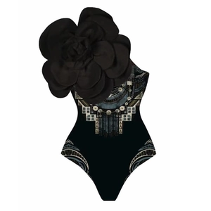 Detail of one-shoulder swimsuit featuring a 3D floral accent and tribal geometric patterns