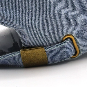Detail of adjustable metal buckle and strap on light blue denim baseball cap