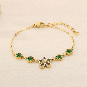 Detail of gold chain bracelet with green star charms and a zircon flower pendant