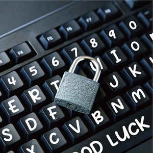 Macro view of a matte dark grey metal padlock on a laptop keyboard for data security