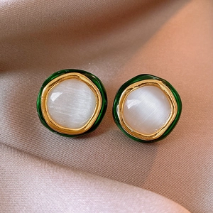 Close-up of gold plated round cat eye stone stud earrings on silk background
