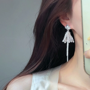 Silver flower stud earrings with long metal tassels and crystal beads on a model