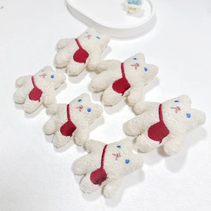 Detail of six cute plush bear patches with blue eyes and red bags for bag decoration