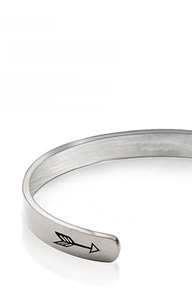 Detail of silver stainless steel cuff bangle showing laser engraved arrow and brushed texture