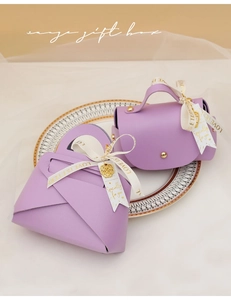 Detail of lilac leather gift boxes with gold charms and ribbon on a porcelain plate