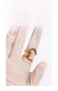 Close-up of golden irregular knotted wide ring with minimalist fluid hollow design