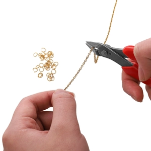 DIY jewelry tool set with red diagonal pliers cutting a gold stainless steel chain link