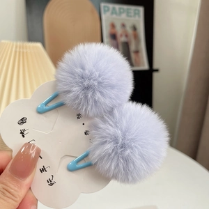 Detailed view of light purple faux fur ball hair clips with blue metal drop clips