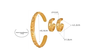 Macro detail of gold-plated bangle and C-shaped earrings with sun and star zircon relief