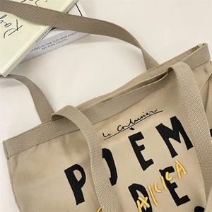Gros plan d'un sac cabas en toile beige avec texte POEM noir et lettrage jaune d'art
