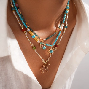 Détail d'un collier bohème multicouche avec turquoise, perles et pendentif soleil sur modèle