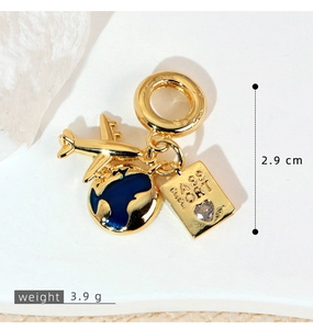 Macro detail of gold travel charms with passport, airplane and blue enamel globe