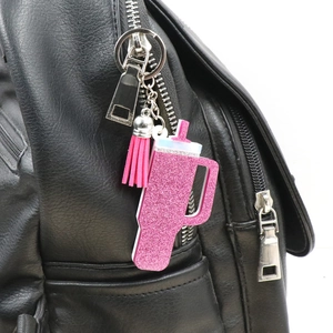 Rosa Glitzer-Becher-Schlüsselanhänger mit Quaste an einem schwarzen Rucksack-Reißverschluss