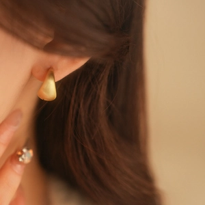 Close-up of matte gold geometric drop earrings on model for a minimalist style