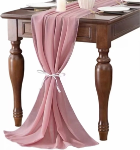 Close-up of elegant pink chiffon table runner tied with a white ribbon on wood table