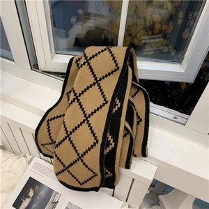 Detail of camel knit scarf featuring black diamond patterns folded on a window sill