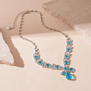 Detailed view of silver necklace with blue teardrop crystal and bow design on stones