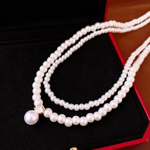 Close-up of double-layer pearl necklace with zircon pendant in a red velvet jewelry box