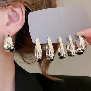 Close-up of minimalist silver water drop earrings featuring a high-polish metallic finish