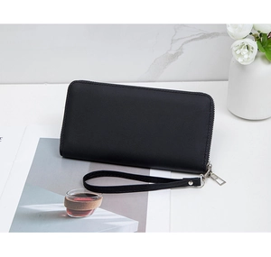 Detail of black long quilted wallet with wrist strap and zipper on marble background