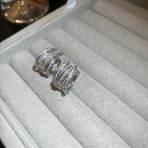 Close-up of silver-tone multi-layer crisscross hoop earrings with pavé white zircons