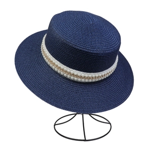 Detail of navy blue flat top straw hat with elegant pearl and gold chain band